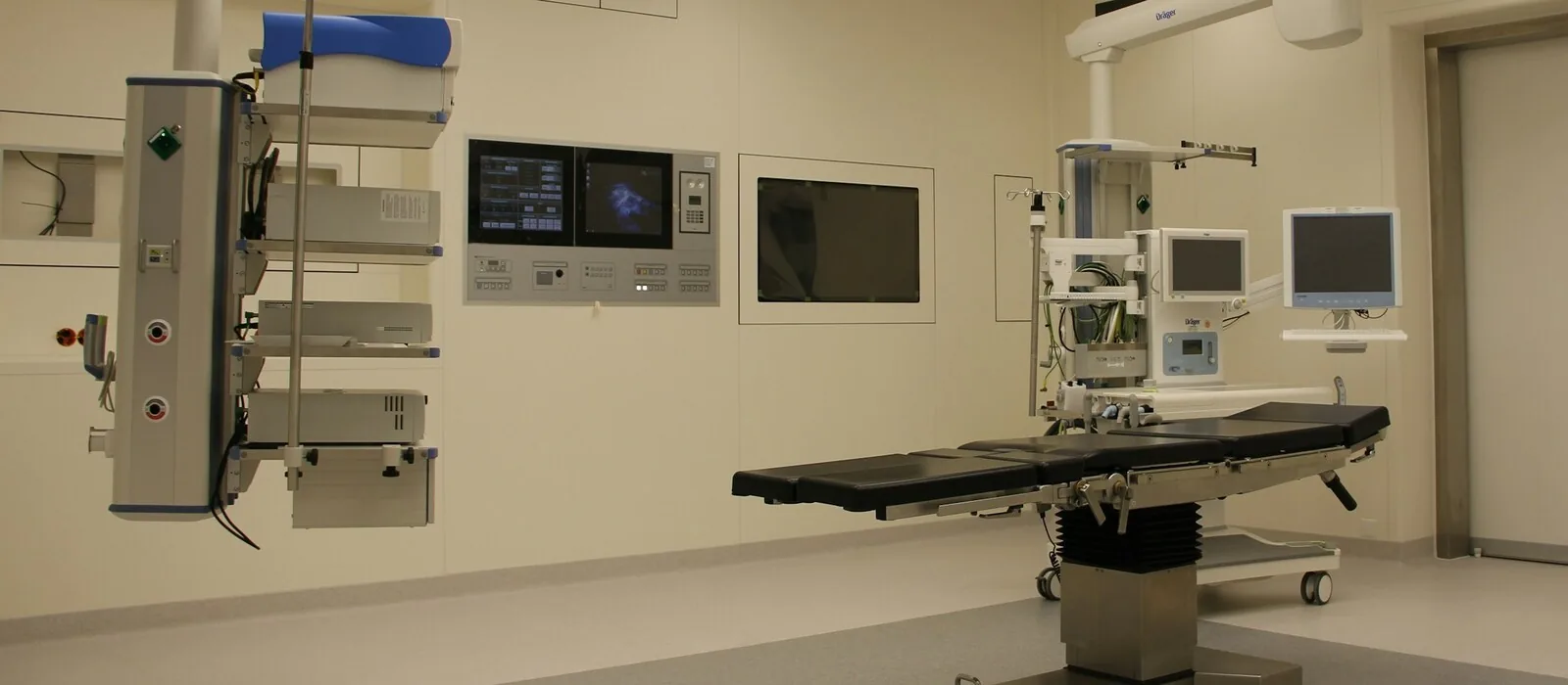 Operating suite with a surgical table, anesthesia machine, ceiling-mounted boom and vital signs monitors