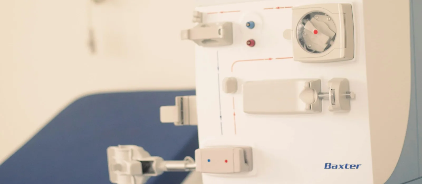 Hemodialysis machine control panel and blood-line connections beside a treatment chair
