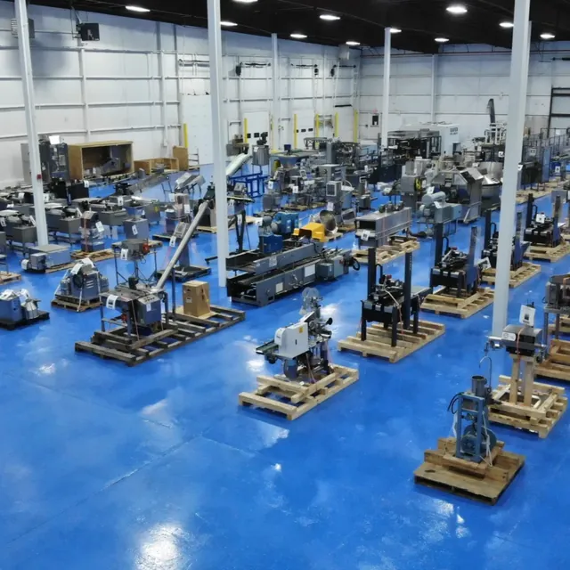 Used packaging and processing machinery on pallets in an equipment warehouse