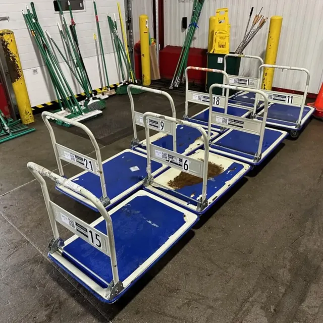 Numbered platform hand trucks lined up in a warehouse