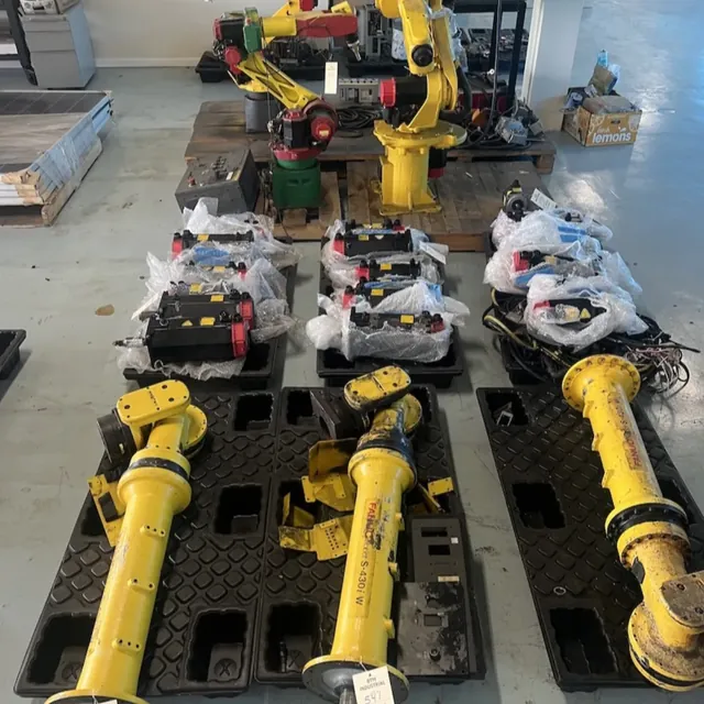 Disassembled FANUC robot arms and servo motors on pallets