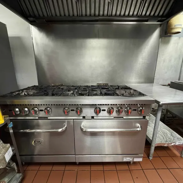 Ten-burner gas range with double ovens under a kitchen exhaust hood