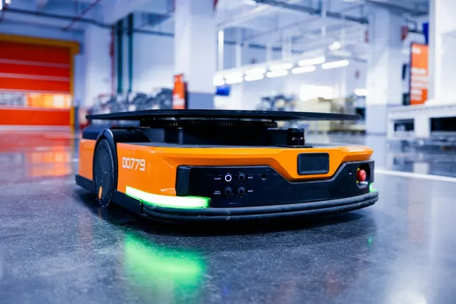 Orange autonomous mobile robot with a lift platform on a polished floor