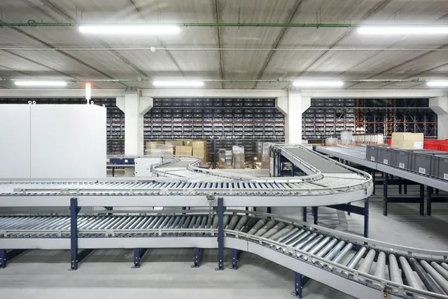 Roller conveyor and sortation curves in a distribution center with automated bin storage behind