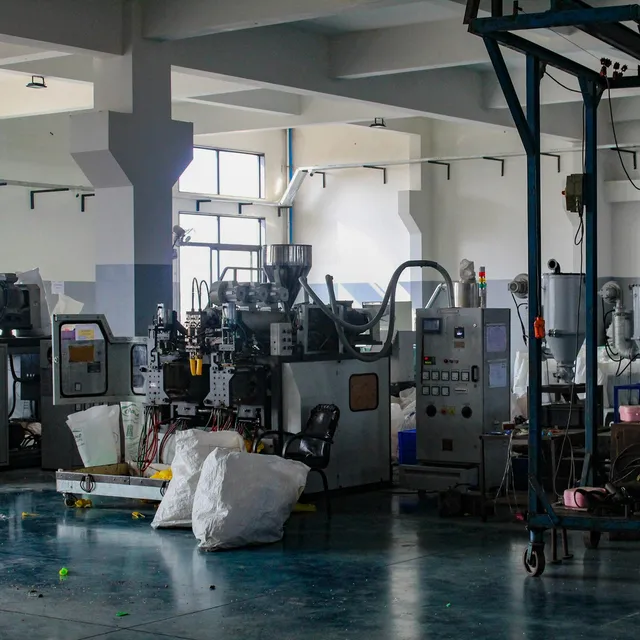 Extrusion blow molding machines with hopper dryers on a plastics plant floor